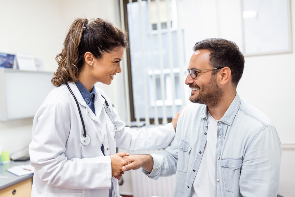 Young woman doctor or GP in white medical uniform consult male patient in private hospital. Female therapist speak talk with man client on consultation in clinic. medicina preventiva después de los 40